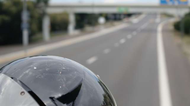Motorcycle helmet, possibly damaged, on a road.
