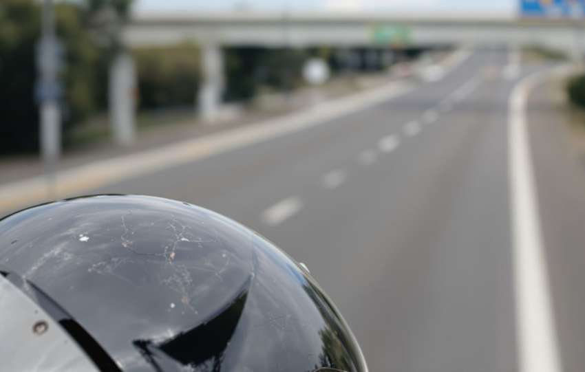 Motorcycle helmet, possibly damaged, on a road.