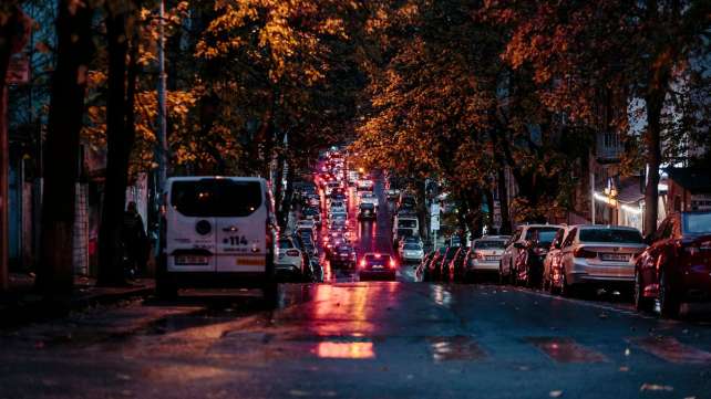 A city street at night with cars parked on the side of the road