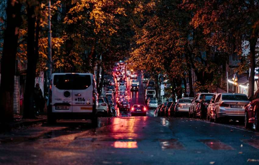 A city street at night with cars parked on the side of the road