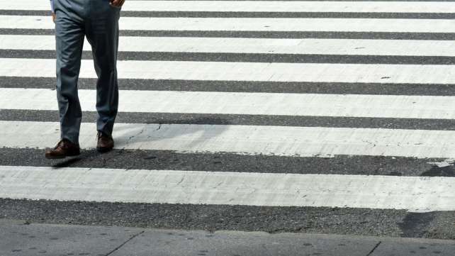 person in blue denim jeans and brown leather shoes standing on pedestrian line