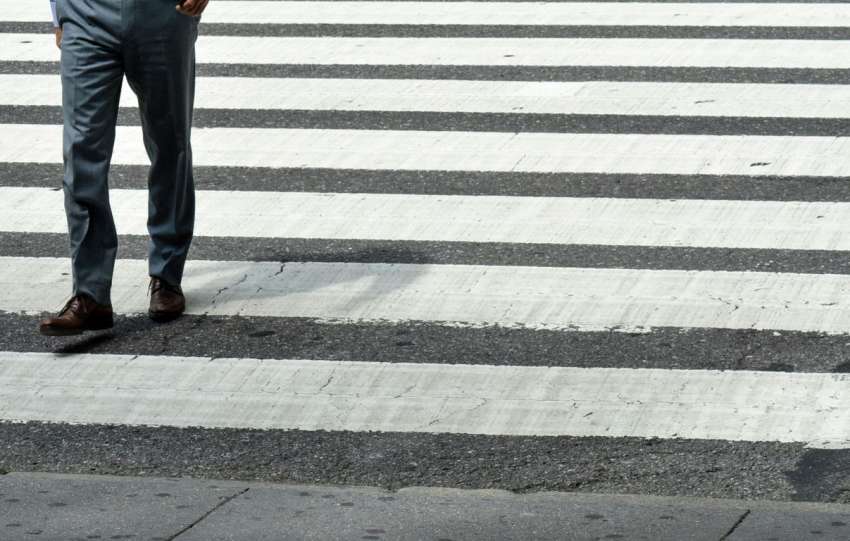person in blue denim jeans and brown leather shoes standing on pedestrian line
